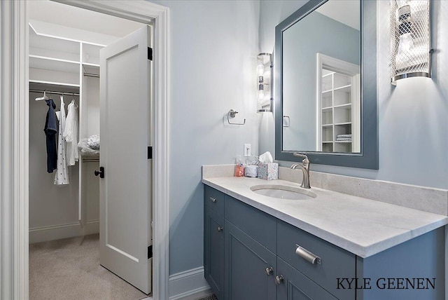 bathroom featuring a spacious closet, baseboards, and vanity
