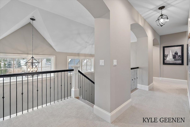 hallway featuring baseboards, vaulted ceiling, carpet flooring, and an upstairs landing