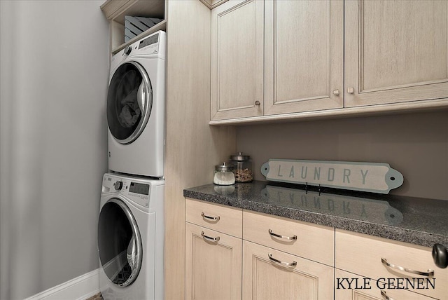 laundry room with cabinet space, baseboards, and stacked washer / dryer