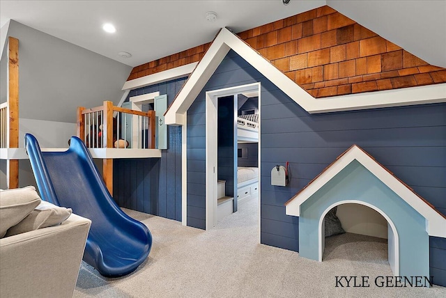 interior space featuring carpet floors, lofted ceiling, wooden walls, and recessed lighting