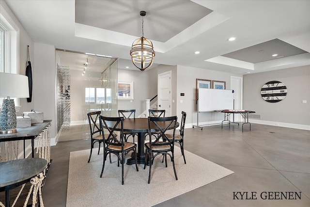 dining room with baseboards, a tray ceiling, and finished concrete floors
