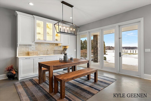 dining space featuring concrete floors, baseboards, and a wealth of natural light