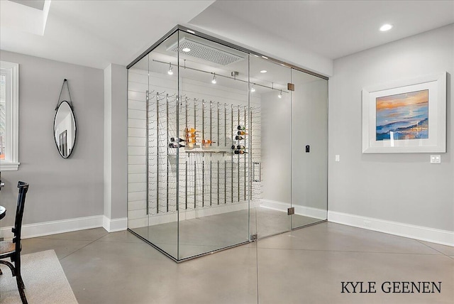 wine room featuring baseboards, recessed lighting, and finished concrete floors
