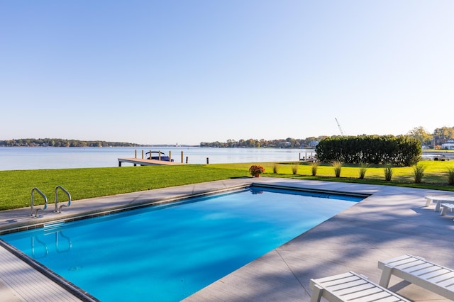 outdoor pool with a dock, a patio area, a water view, and a lawn