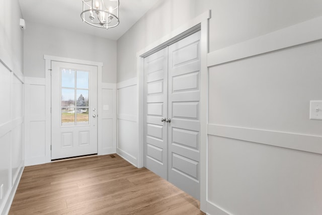 interior space with a notable chandelier, a decorative wall, wood finished floors, and wainscoting