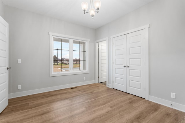 unfurnished bedroom with visible vents, baseboards, light wood-style floors, a closet, and an inviting chandelier