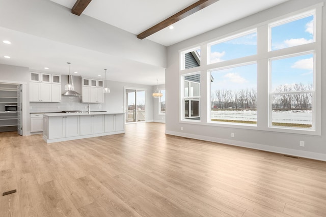 unfurnished living room featuring recessed lighting, beam ceiling, light wood-style flooring, and baseboards