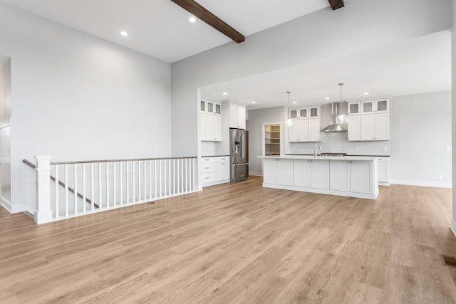 unfurnished living room featuring baseboards, beamed ceiling, light wood-style flooring, and recessed lighting