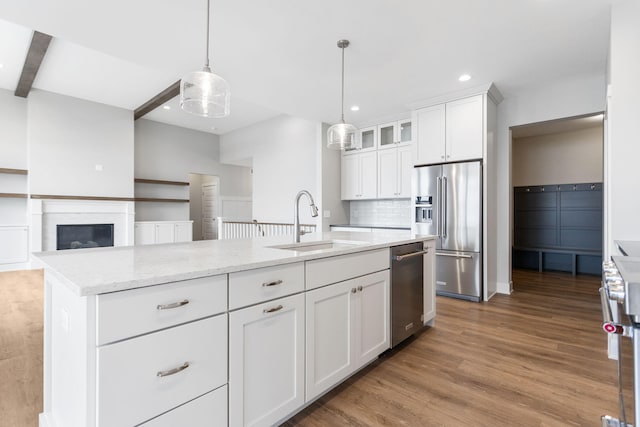 kitchen featuring high quality appliances, glass insert cabinets, wood finished floors, white cabinetry, and a sink