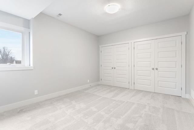 unfurnished bedroom with light carpet, visible vents, baseboards, and two closets