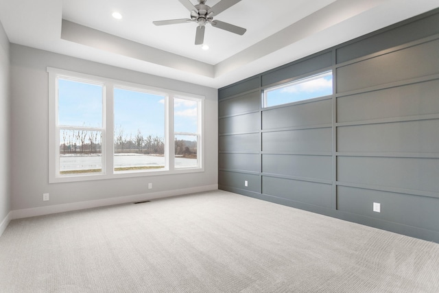 empty room featuring baseboards, recessed lighting, a raised ceiling, and light colored carpet