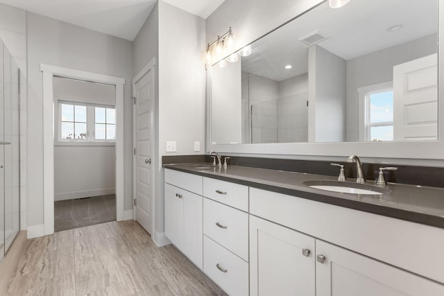 full bath with a stall shower, visible vents, a sink, and wood finished floors