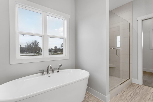 bathroom featuring a stall shower, baseboards, and a freestanding bath