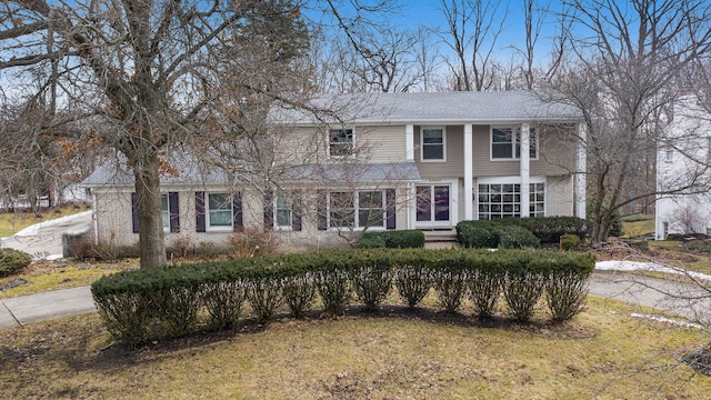 traditional-style house featuring brick siding and a front lawn