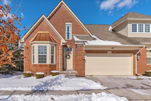 view of front of house featuring a garage, driveway, a shingled roof, and brick siding