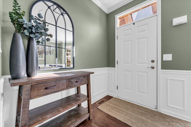 foyer entrance with a healthy amount of sunlight, crown molding, dark wood-type flooring, and wainscoting