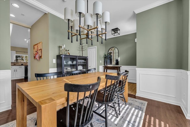 dining area featuring recessed lighting, dark wood-type flooring, wainscoting, an inviting chandelier, and crown molding