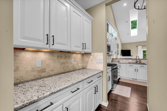 kitchen featuring stainless steel appliances, white cabinets, a sink, and light stone counters