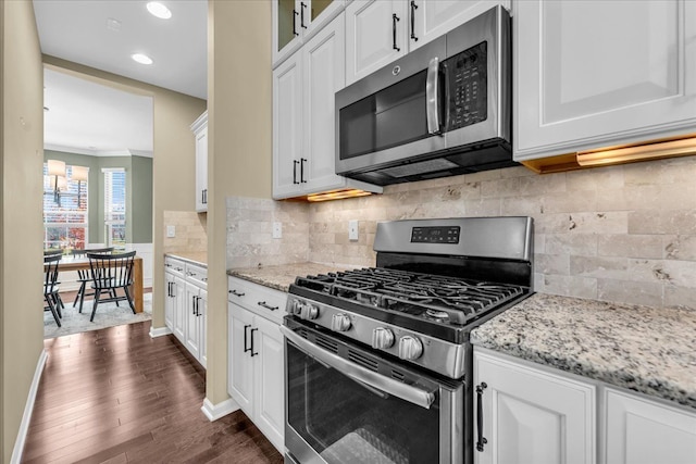 kitchen featuring appliances with stainless steel finishes, glass insert cabinets, dark wood-type flooring, white cabinetry, and light stone countertops