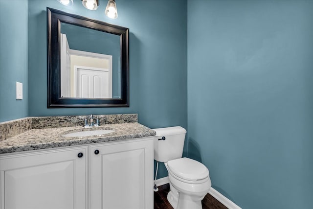 bathroom with baseboards, vanity, toilet, and wood finished floors