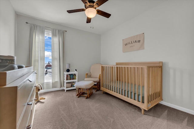 carpeted bedroom with a crib, ceiling fan, and baseboards