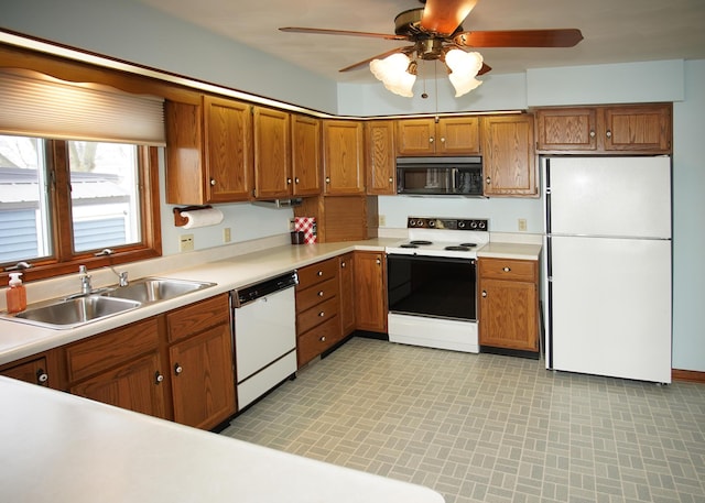 kitchen featuring white appliances, brown cabinetry, and a sink