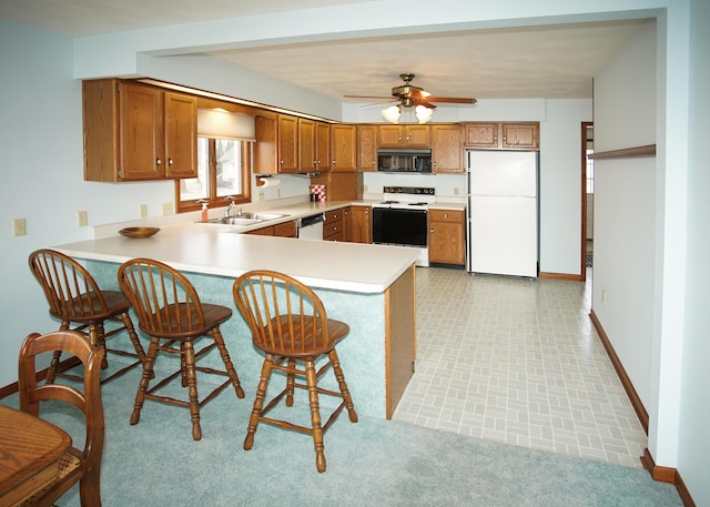 kitchen featuring electric range oven, black microwave, brown cabinetry, and freestanding refrigerator