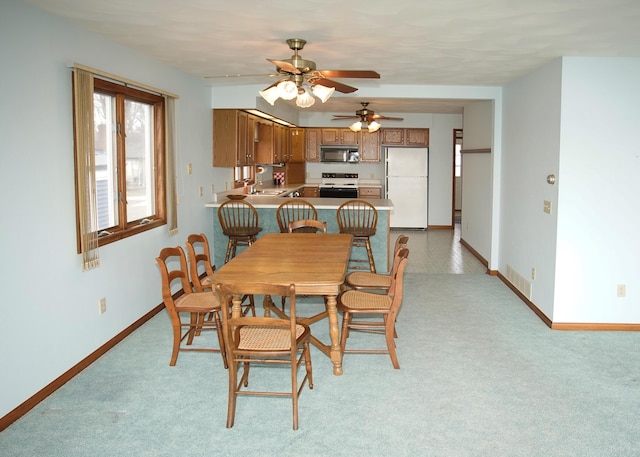 dining space with a ceiling fan, light colored carpet, visible vents, and baseboards