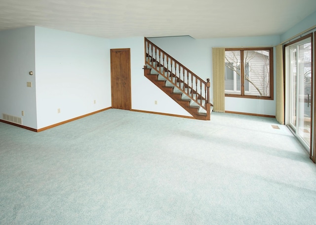 unfurnished living room featuring carpet flooring, visible vents, baseboards, and stairs