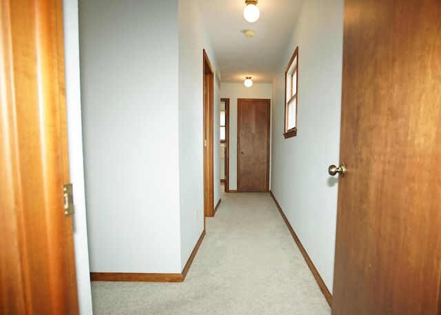 hallway with light colored carpet and baseboards