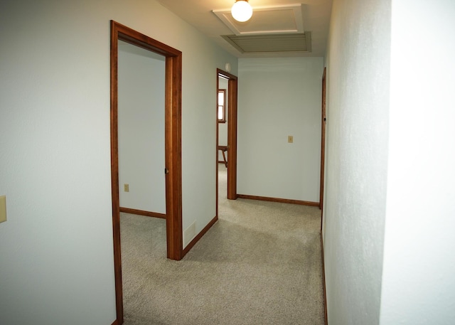 hallway with carpet floors, attic access, and baseboards