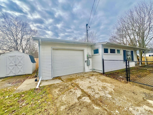 garage with a storage shed, fence, and concrete driveway