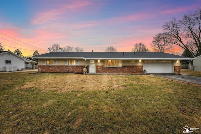 single story home with driveway, a yard, an attached garage, and brick siding