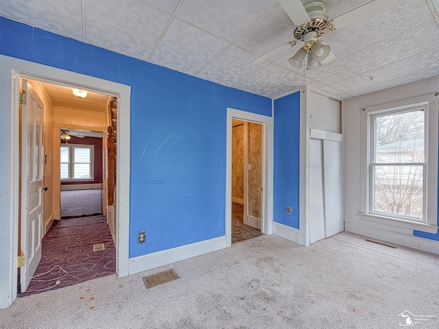 unfurnished bedroom featuring carpet floors, ceiling fan, baseboards, and a closet