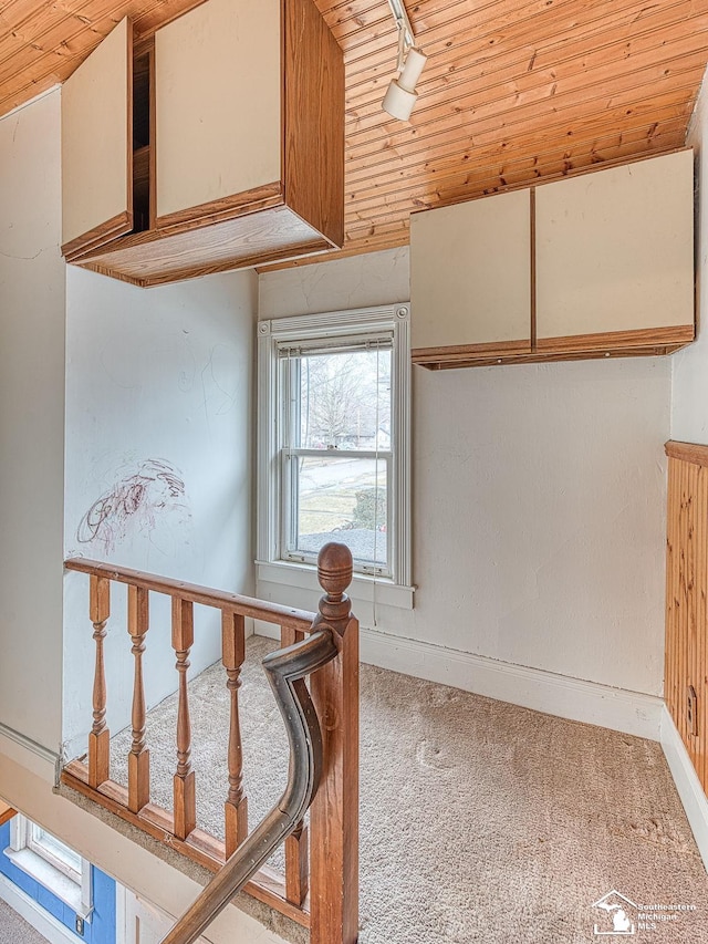 corridor featuring wooden ceiling, carpet, baseboards, and track lighting