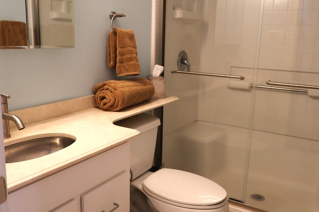bathroom featuring toilet, a stall shower, and vanity