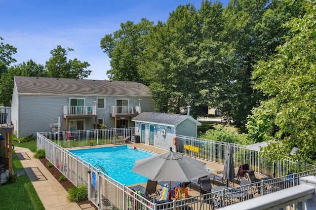 view of swimming pool with an outbuilding, a patio, fence, and a fenced in pool