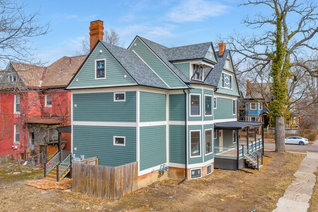 4301 Avery St, Detroit, MI 48208 - view of side of home with a chimney, a porch, fence, roof with shingles, and stairs