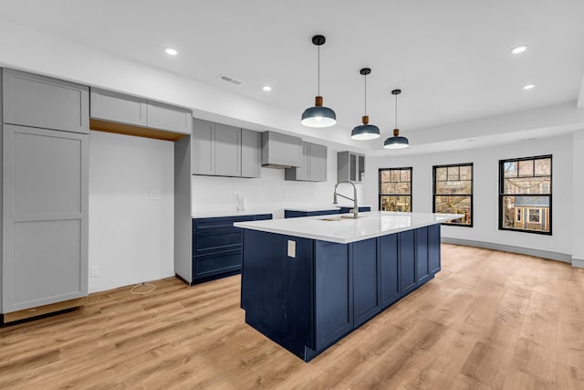 kitchen with light wood-style floors, recessed lighting, a sink, and an island with sink