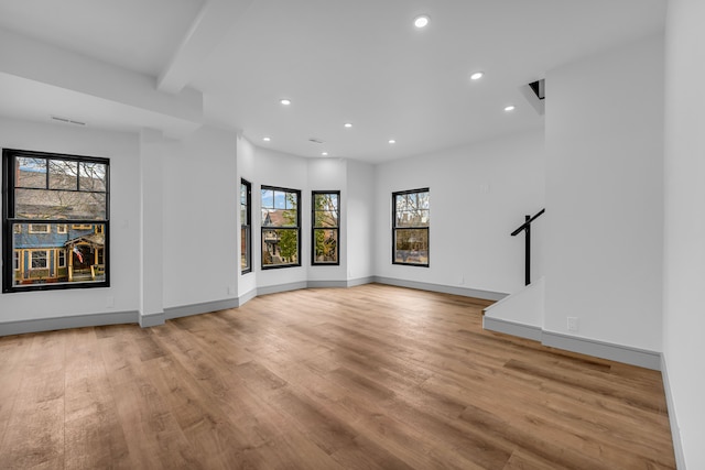 unfurnished living room with light wood-style flooring, baseboards, beamed ceiling, and recessed lighting