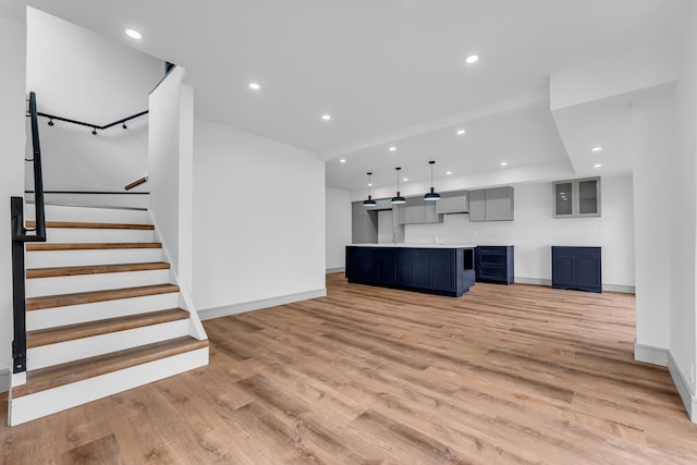 unfurnished living room with baseboards, stairway, light wood-type flooring, and recessed lighting