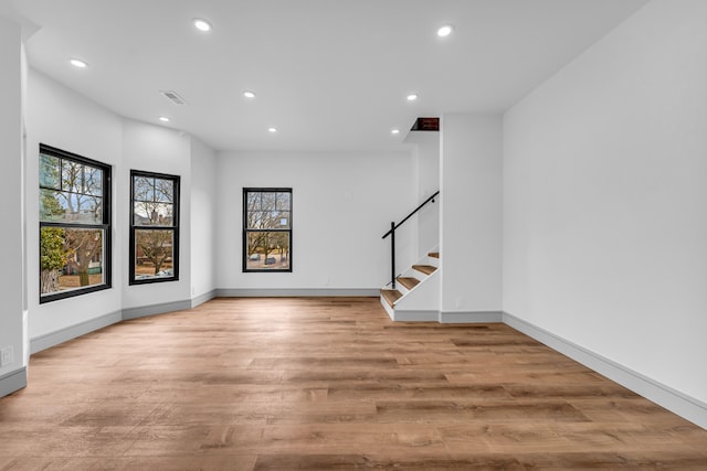 spare room featuring light wood-type flooring, stairway, and recessed lighting