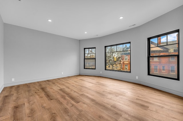 empty room featuring light wood finished floors, baseboards, and recessed lighting