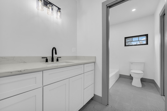 full bath featuring toilet, a bathing tub, vanity, baseboards, and tile patterned floors