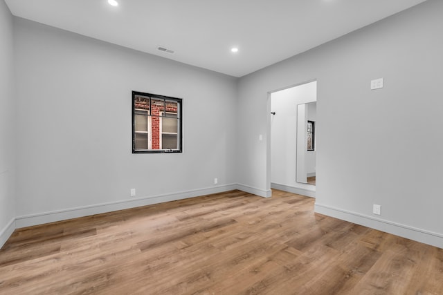 unfurnished room with baseboards, wood finished floors, visible vents, and recessed lighting