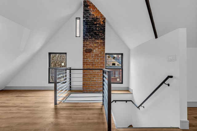 bonus room with light wood-style floors and high vaulted ceiling