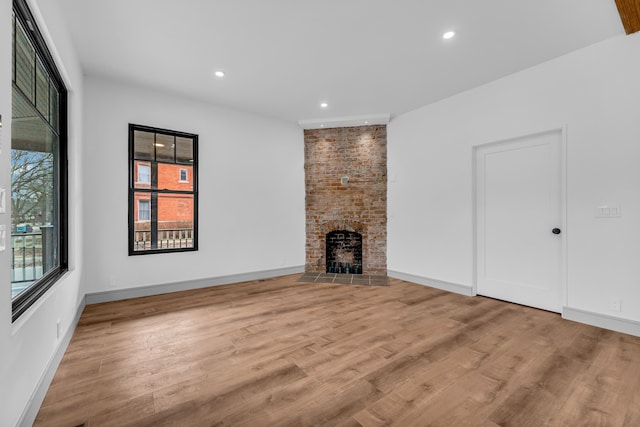 unfurnished living room featuring recessed lighting, a fireplace, baseboards, and wood finished floors