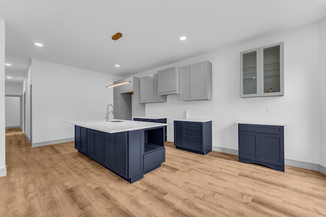 kitchen featuring a center island with sink, a sink, light wood-style flooring, and recessed lighting