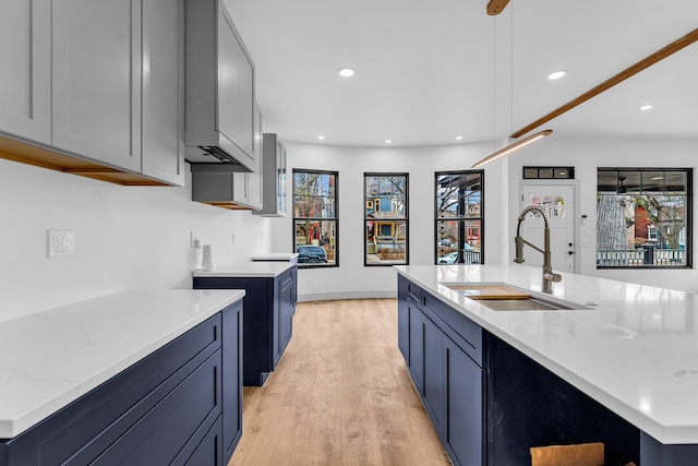 kitchen with recessed lighting, light wood-type flooring, a sink, and light stone countertops