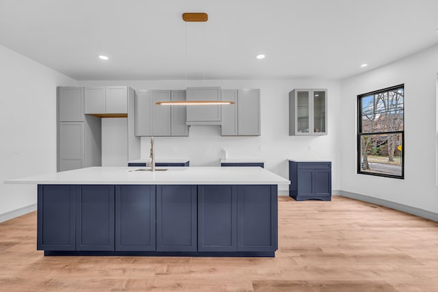 kitchen with light wood-style floors, a center island with sink, baseboards, and recessed lighting